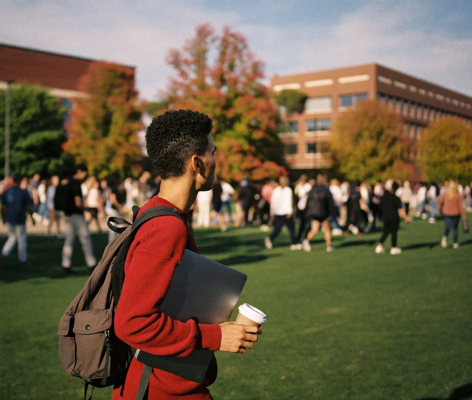 Students crossing a college campus lawn on an autumn afternoon.